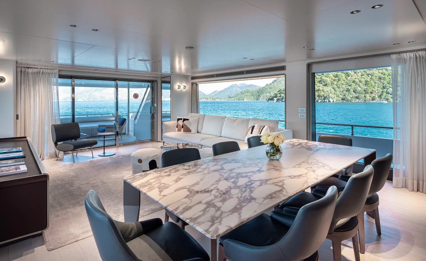 The salon features a luxurious dining area with a marble table and comfortable seating, offering stunning views of the sea. aboard BELLE ILE Yacht for Sale