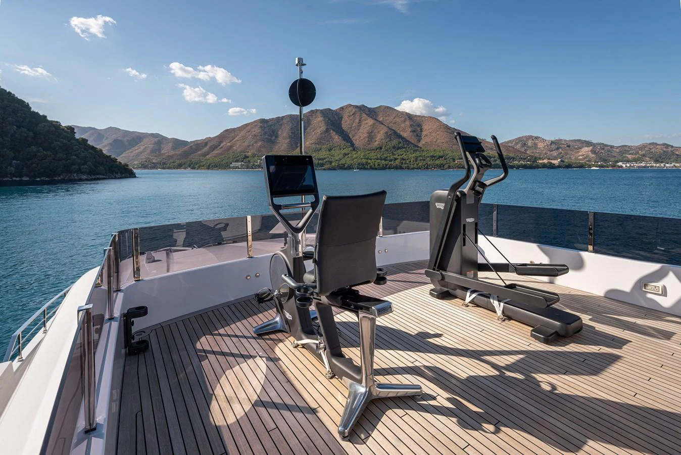 The yacht features an open-air gym with stunning views of the surrounding waters and mountains. aboard BELLE ILE Yacht for Sale