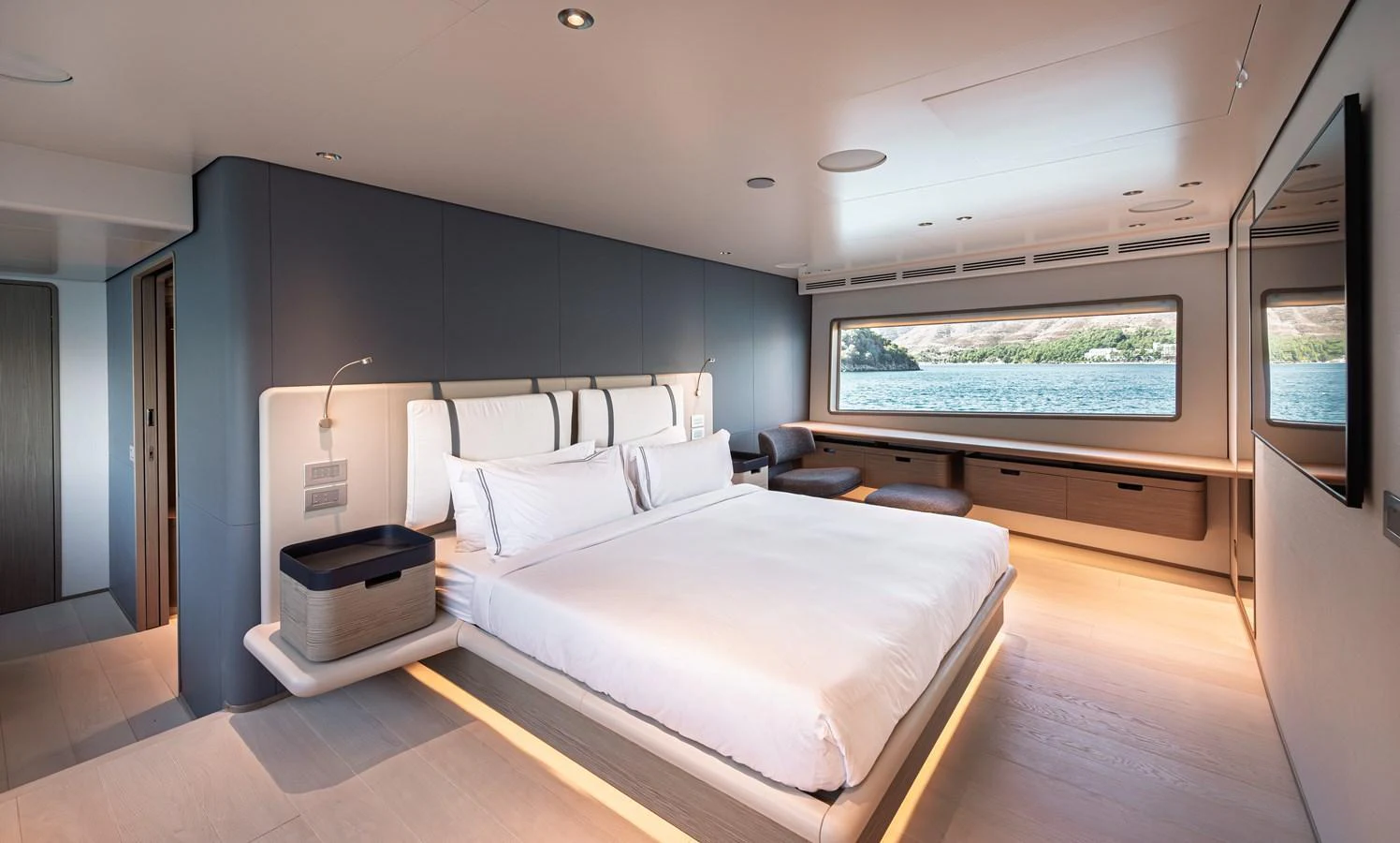 The master stateroom features a spacious bed, modern furnishings, and a large window with a stunning view of the water. aboard BELLE ILE Yacht for Sale