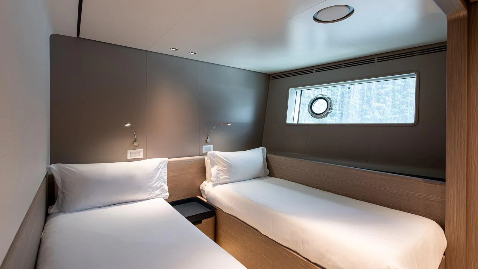 The twin stateroom features two single beds with modern lighting and a large window for natural light. aboard BELLE ILE Yacht for Sale