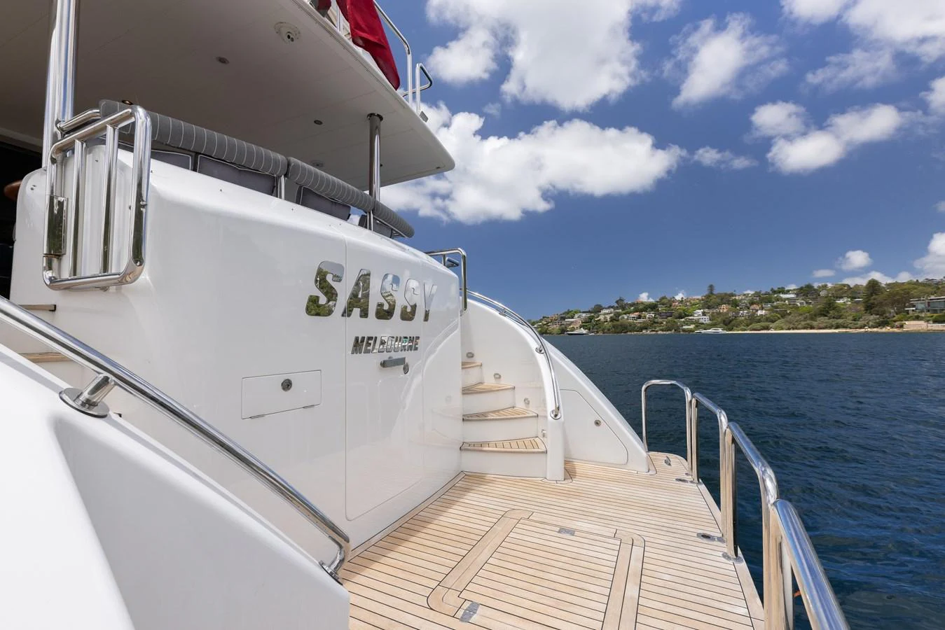 The yacht's sleek exterior features a pristine deck and elegant curves, set against a beautiful coastal backdrop. aboard SASSY Yacht for Sale