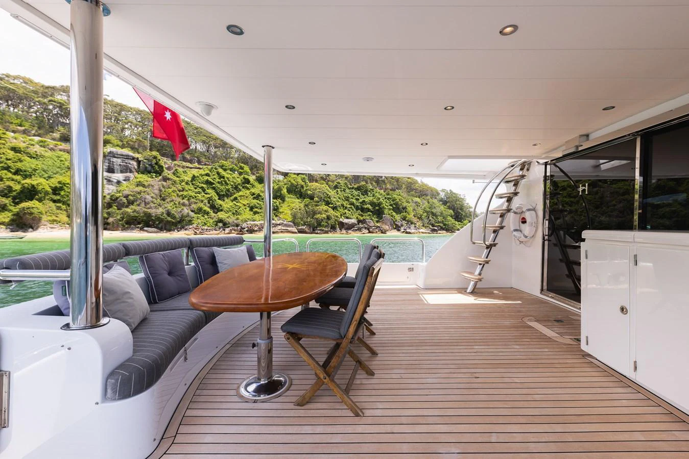 The aft deck features a comfortable seating area with a dining table and chairs, perfect for outdoor relaxation. aboard SASSY Yacht for Sale