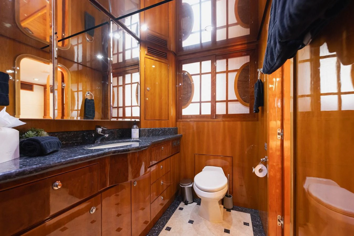 The yacht's bathroom features elegant wood paneling and a sleek granite countertop. aboard SASSY Yacht for Sale