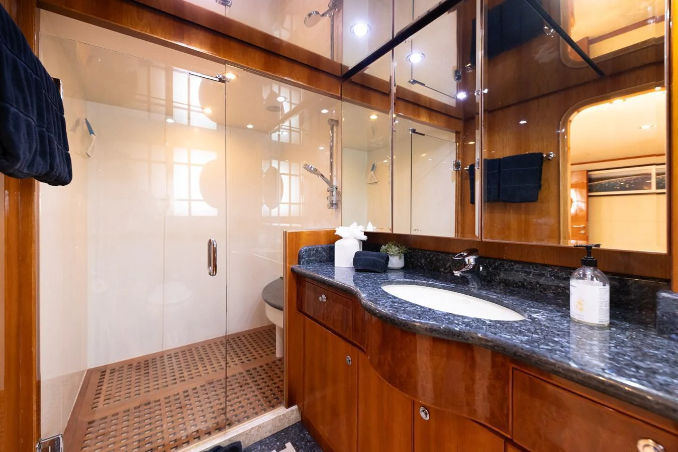 This luxurious yacht bathroom features elegant wood finishes and a spacious glass-enclosed shower. aboard SASSY Yacht for Sale