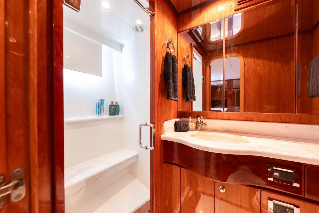 The yacht's bathroom features elegant wood finishes and a sleek, modern shower area. aboard SASSY Yacht for Sale
