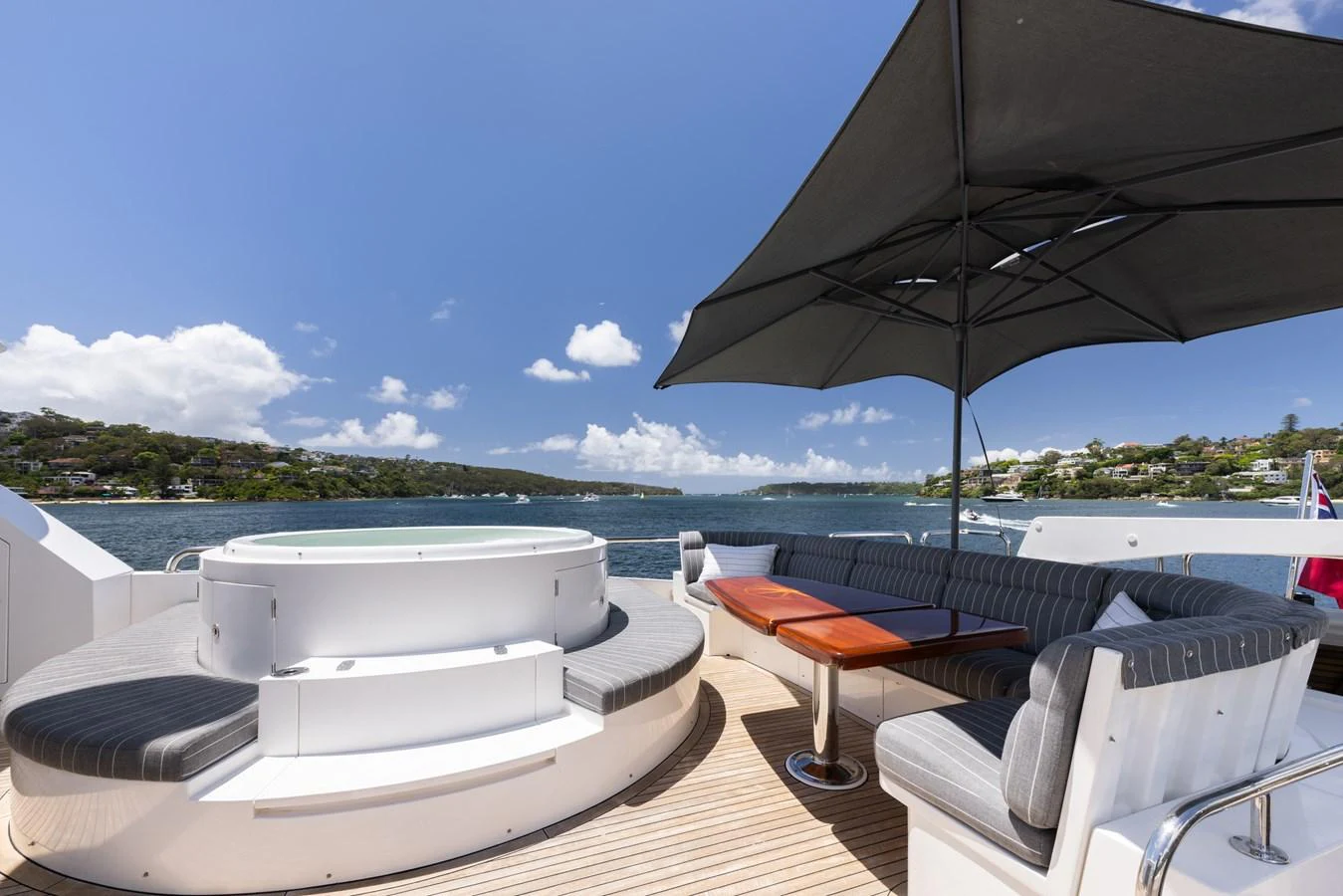 The sundeck features a luxurious hot tub and comfortable seating area under a large parasol, perfect for relaxation and enjoying the view. aboard SASSY Yacht for Sale