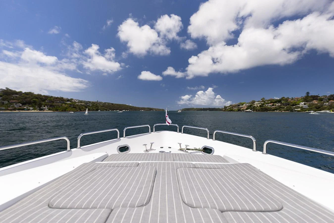 The yacht's bow offers a serene view of the surrounding waters and coastline under a bright, partly cloudy sky. aboard SASSY Yacht for Sale