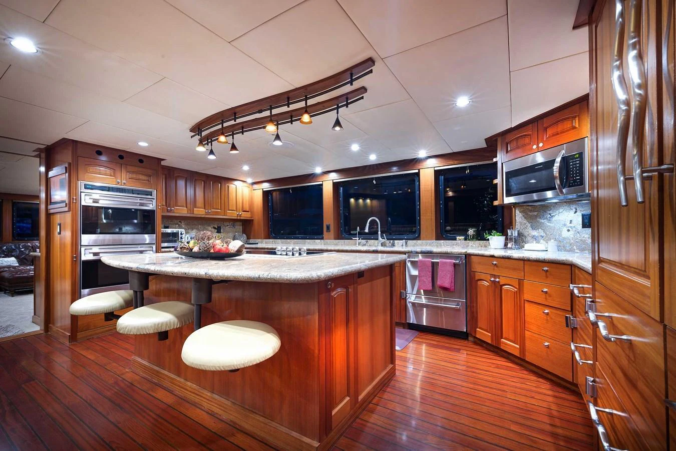 The yacht's galley features luxurious wooden cabinetry, a large island with seating, and modern appliances. aboard HEAVEN'S GATE Yacht for Sale