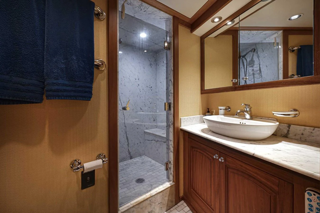 The yacht's bathroom features a luxurious marble shower and elegant wooden cabinetry. aboard HEAVEN'S GATE Yacht for Sale