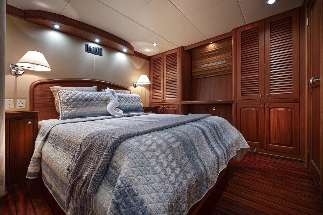 The stateroom features a cozy bed with elegant wood paneling and ambient lighting. aboard HEAVEN'S GATE Yacht for Sale