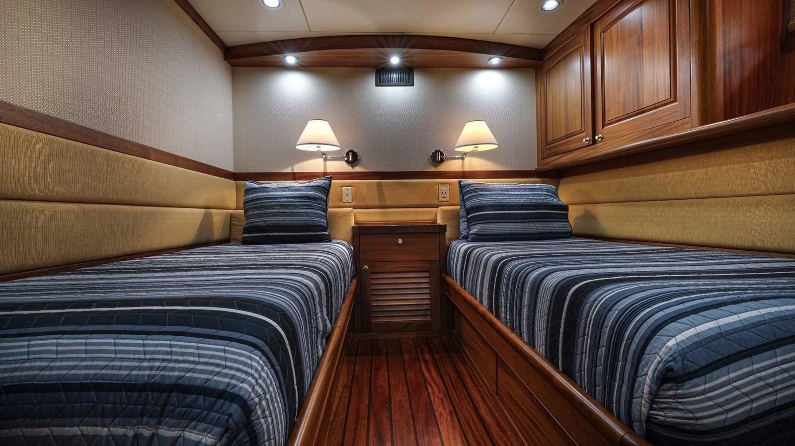 The twin stateroom features two comfortable beds with elegant wood finishes and ambient lighting. aboard HEAVEN'S GATE Yacht for Sale
