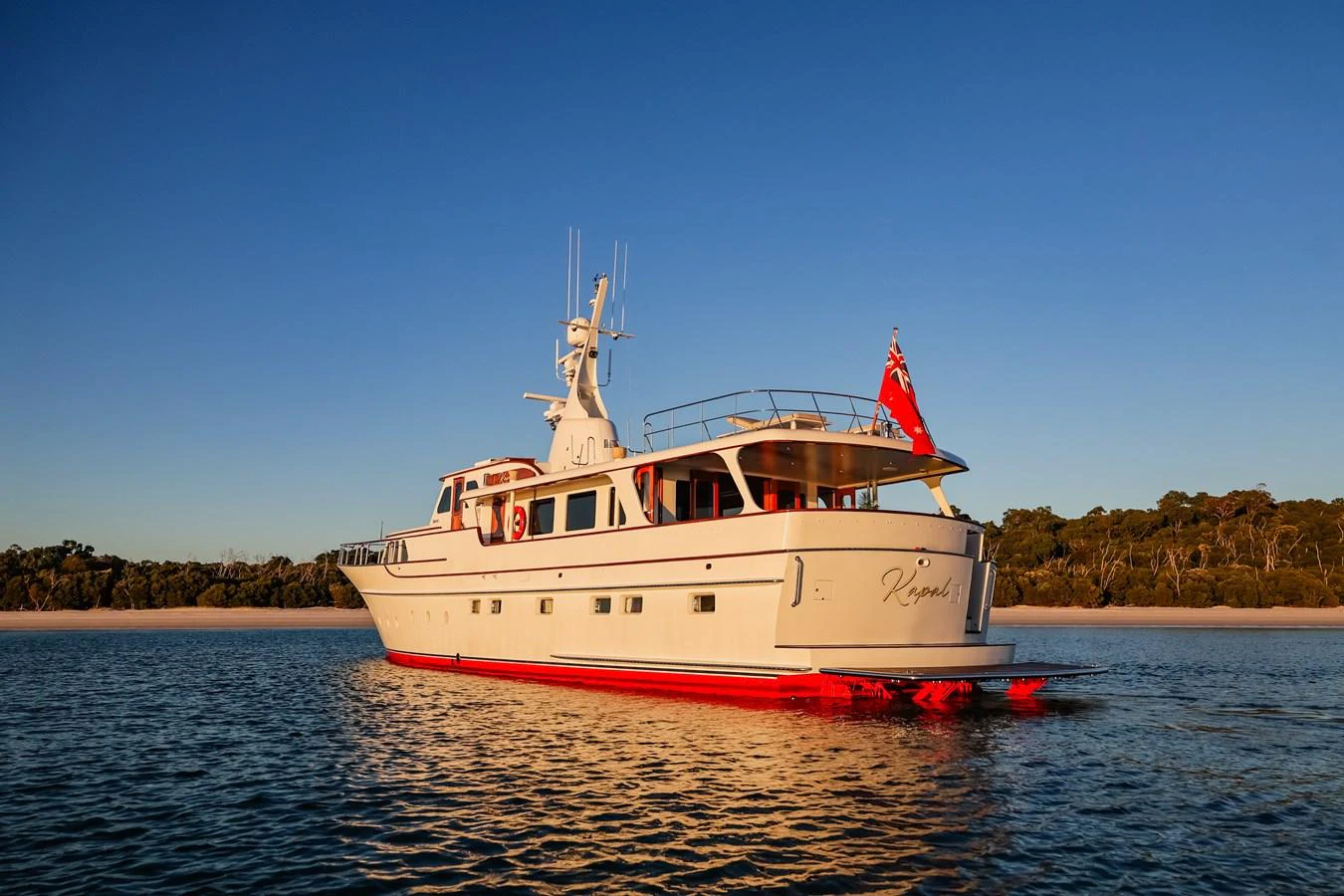 A classic motor yacht with a sleek profile, cruising on calm waters during sunset. aboard VICTORIA Yacht for Sale