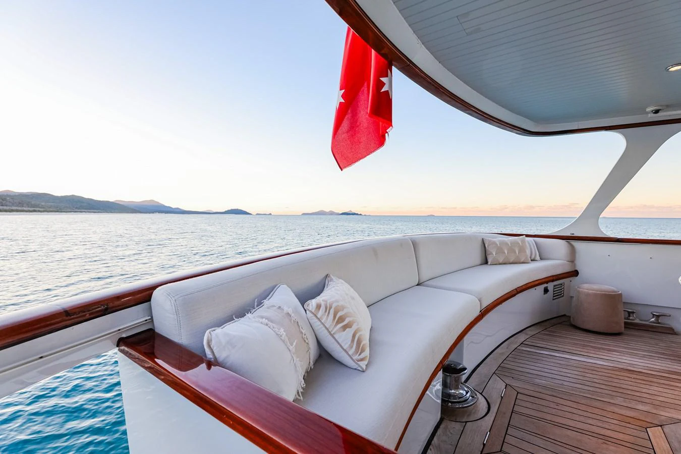 The aft deck features a comfortable curved seating area with plush cushions, perfect for enjoying the serene ocean views. aboard VICTORIA Yacht for Sale