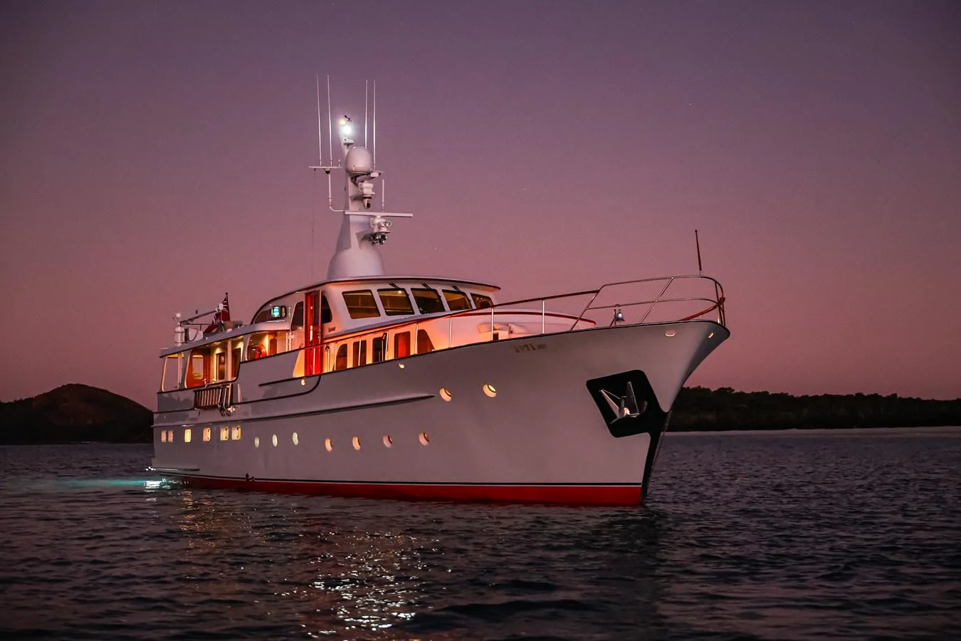 A classic yacht is beautifully illuminated at dusk, cruising on calm waters. aboard VICTORIA Yacht for Sale