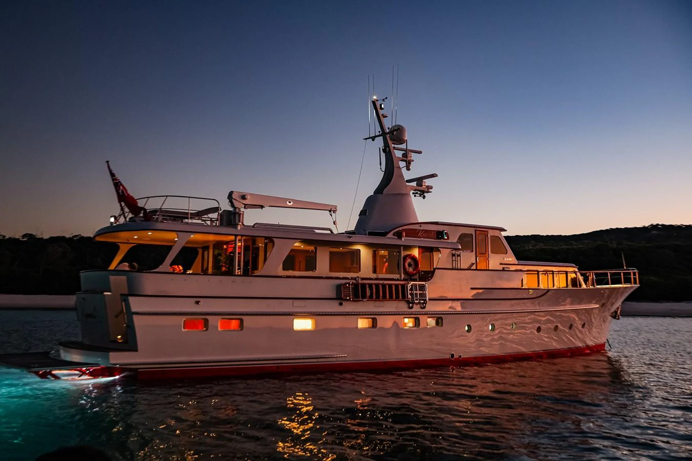 A classic yacht is beautifully illuminated at dusk, showcasing its elegant lines and inviting ambiance. aboard VICTORIA Yacht for Sale