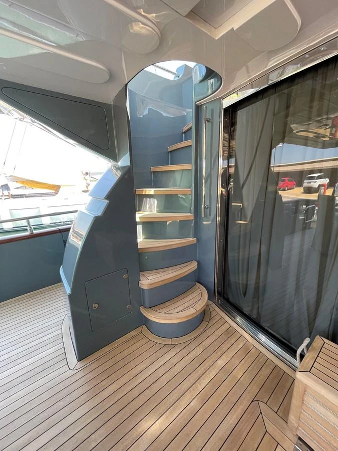 A stylish spiral staircase with wooden steps leads to the upper deck, complemented by sleek, modern design elements. aboard UNICA Yacht for Sale