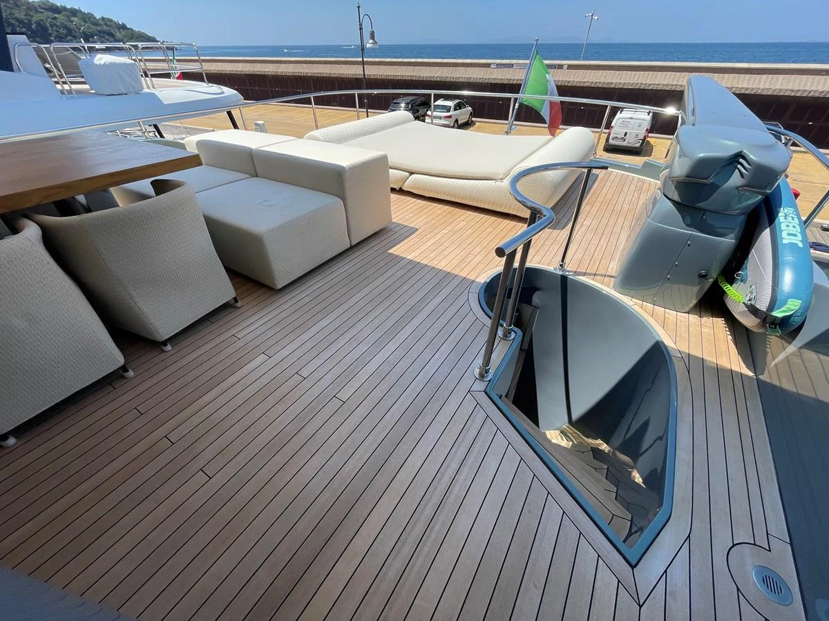 The aft deck features a spacious lounging area with comfortable seating and a staircase leading below deck. aboard UNICA Yacht for Sale