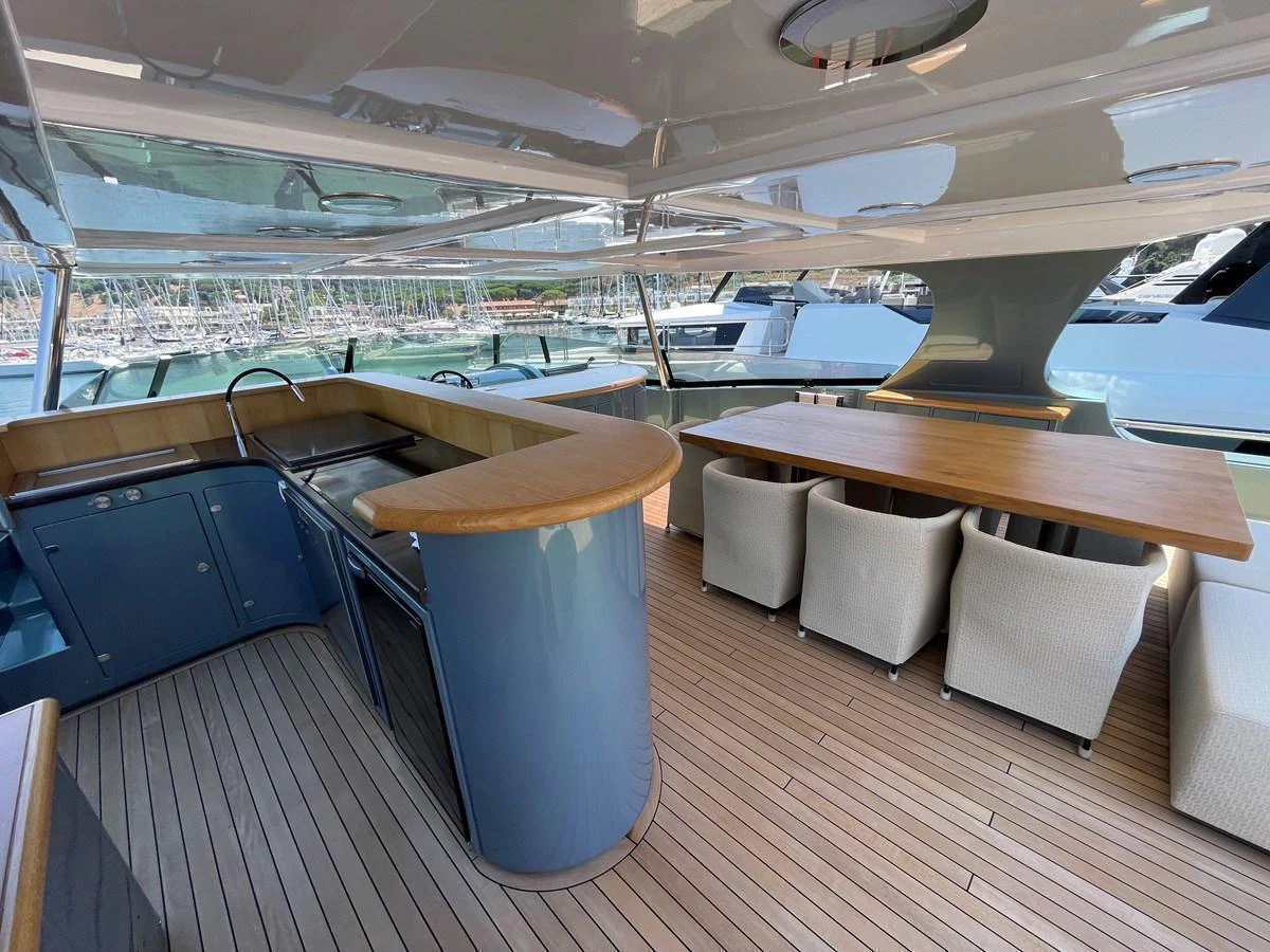 The flybridge features a sleek bar area and a spacious dining table with comfortable seating. aboard UNICA Yacht for Sale