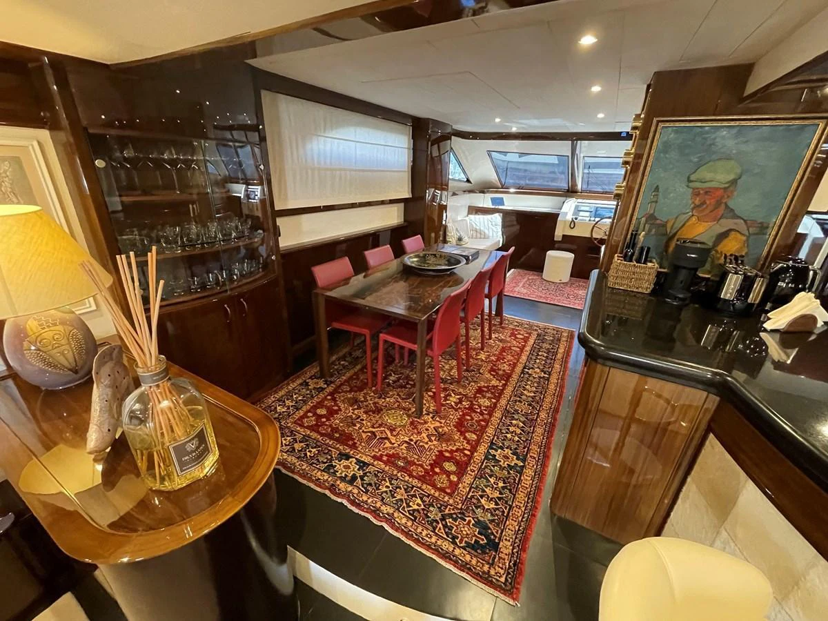 The yacht's dining area features a rich, inviting ambiance with elegant furnishings and decor. aboard UNICA Yacht for Sale