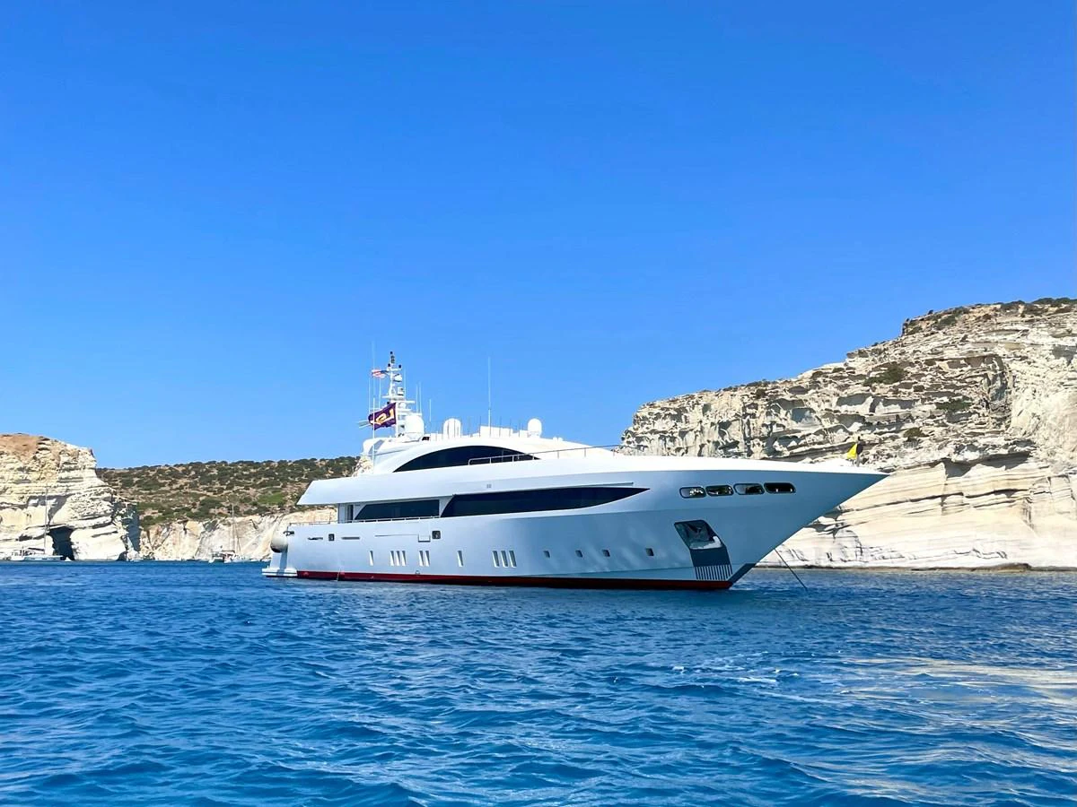 A sleek and modern yacht is anchored in a serene coastal area with stunning cliffs in the background. aboard BARENTS SEA Yacht for Sale