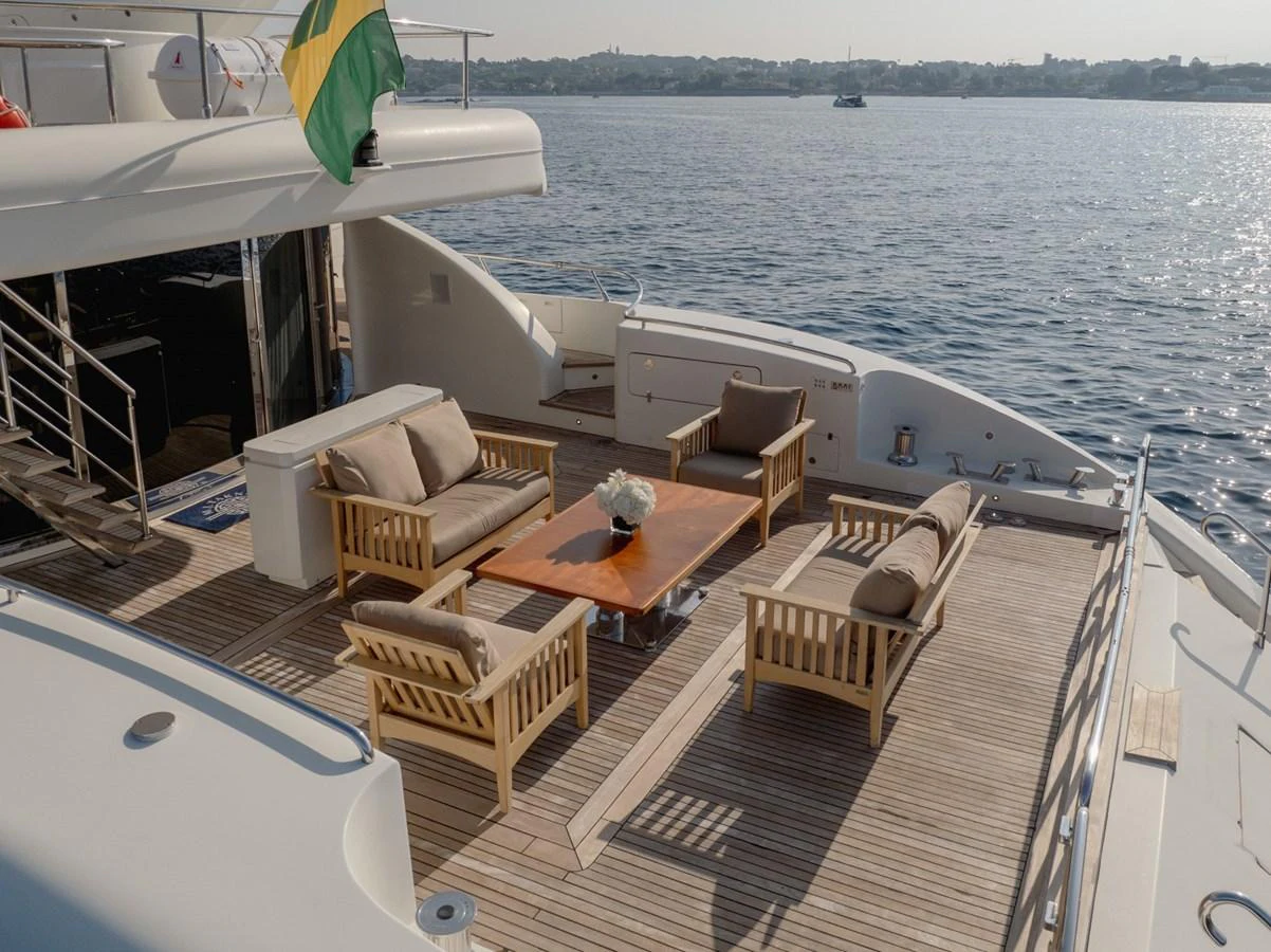 The aft deck features a comfortable seating area with wooden furniture and a central table, perfect for relaxation and socializing. aboard M.J. TAKNM Yacht for Sale