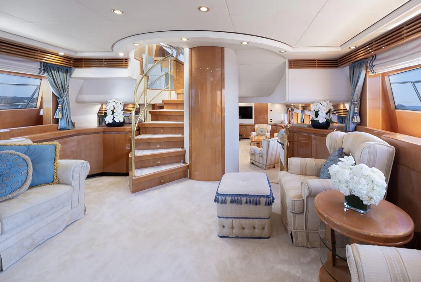 The salon features elegant furnishings and a spiral staircase, creating a luxurious and inviting atmosphere. aboard M.J. TAKNM Yacht for Sale