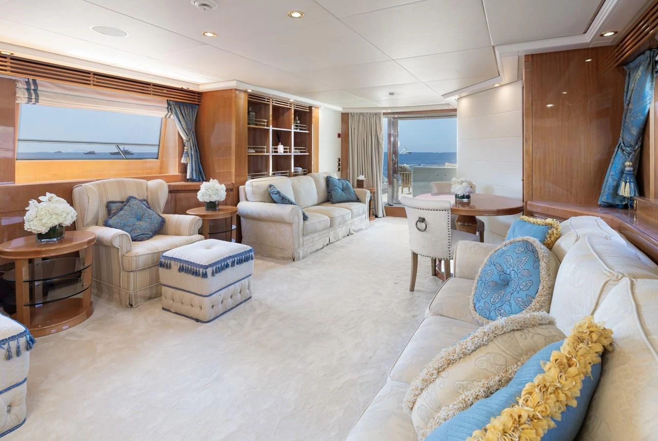 The yacht's salon features elegant seating with plush cushions and a serene ocean view through large windows. aboard M.J. TAKNM Yacht for Sale