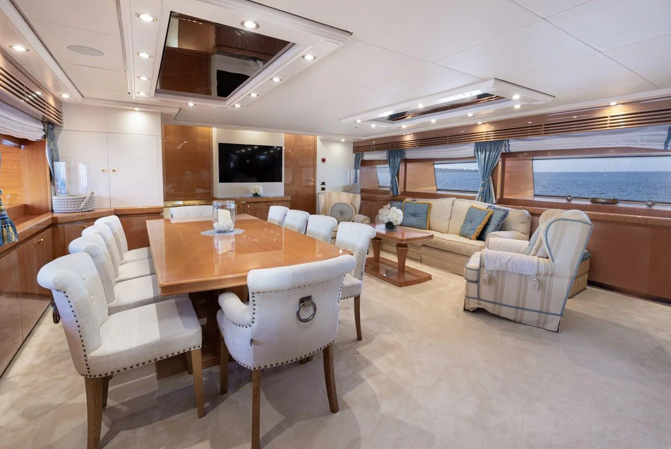 The spacious salon features a large dining table and comfortable seating with panoramic ocean views. aboard M.J. TAKNM Yacht for Sale