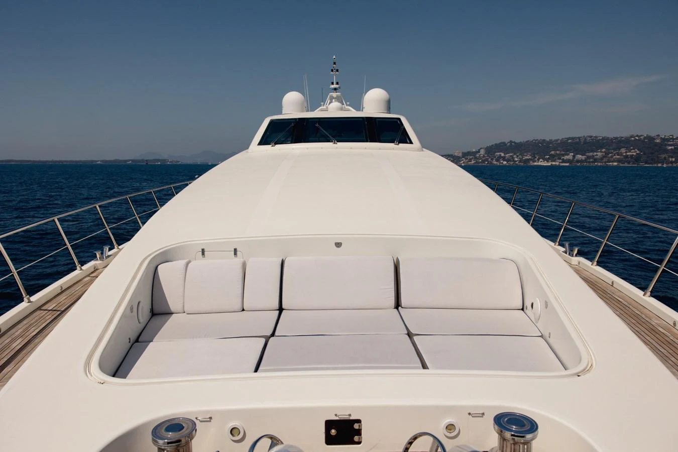 The yacht's sleek foredeck offers a spacious sunbathing area with plush cushions, set against a backdrop of serene waters and distant coastline. aboard M.J. TAKNM Yacht for Sale