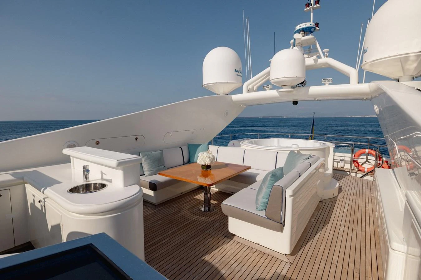 The flybridge offers a luxurious outdoor seating area with a dining table and panoramic ocean views. aboard M.J. TAKNM Yacht for Sale