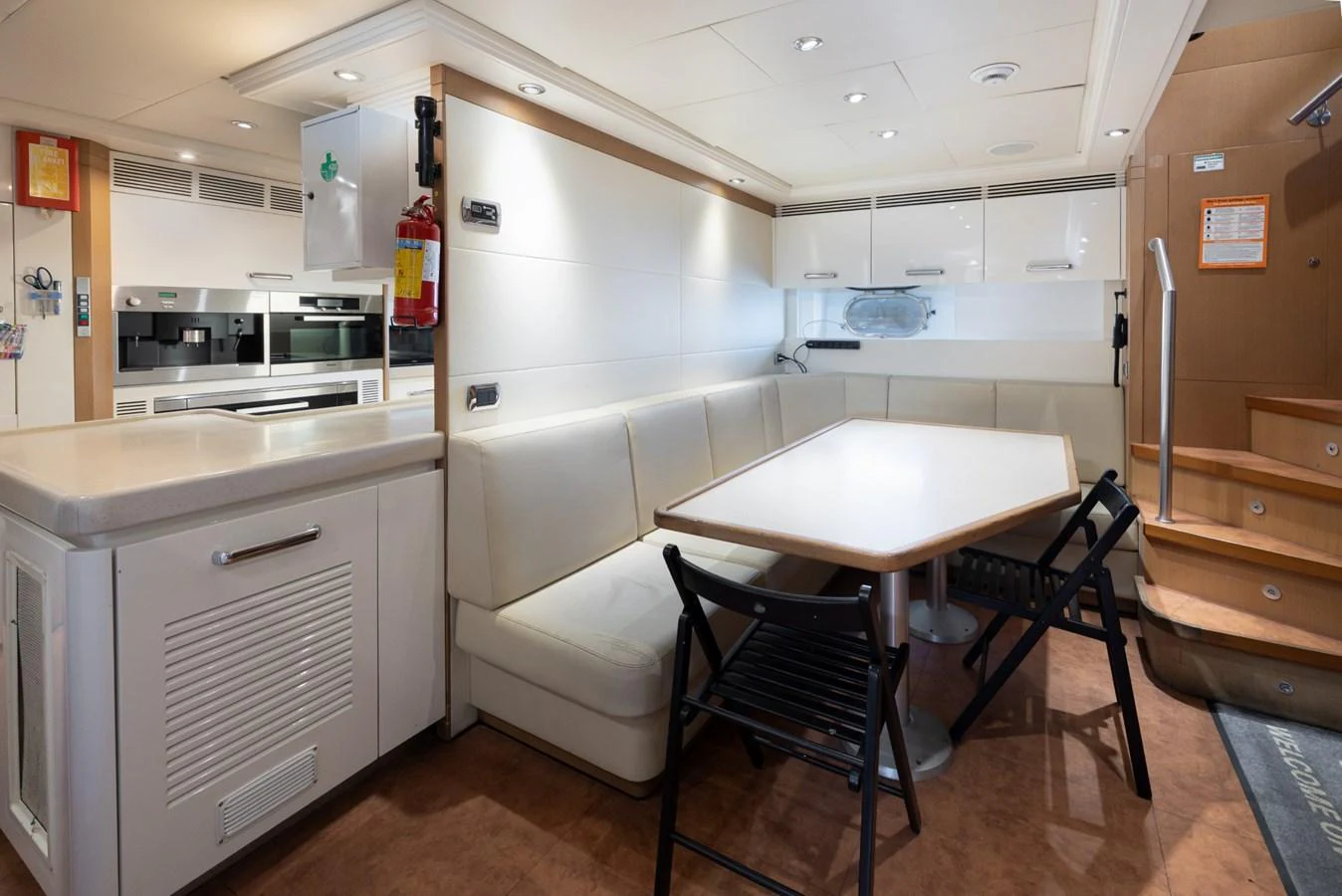 The galley features a cozy dining area with a built-in bench and modern kitchen appliances. aboard M.J. TAKNM Yacht for Sale