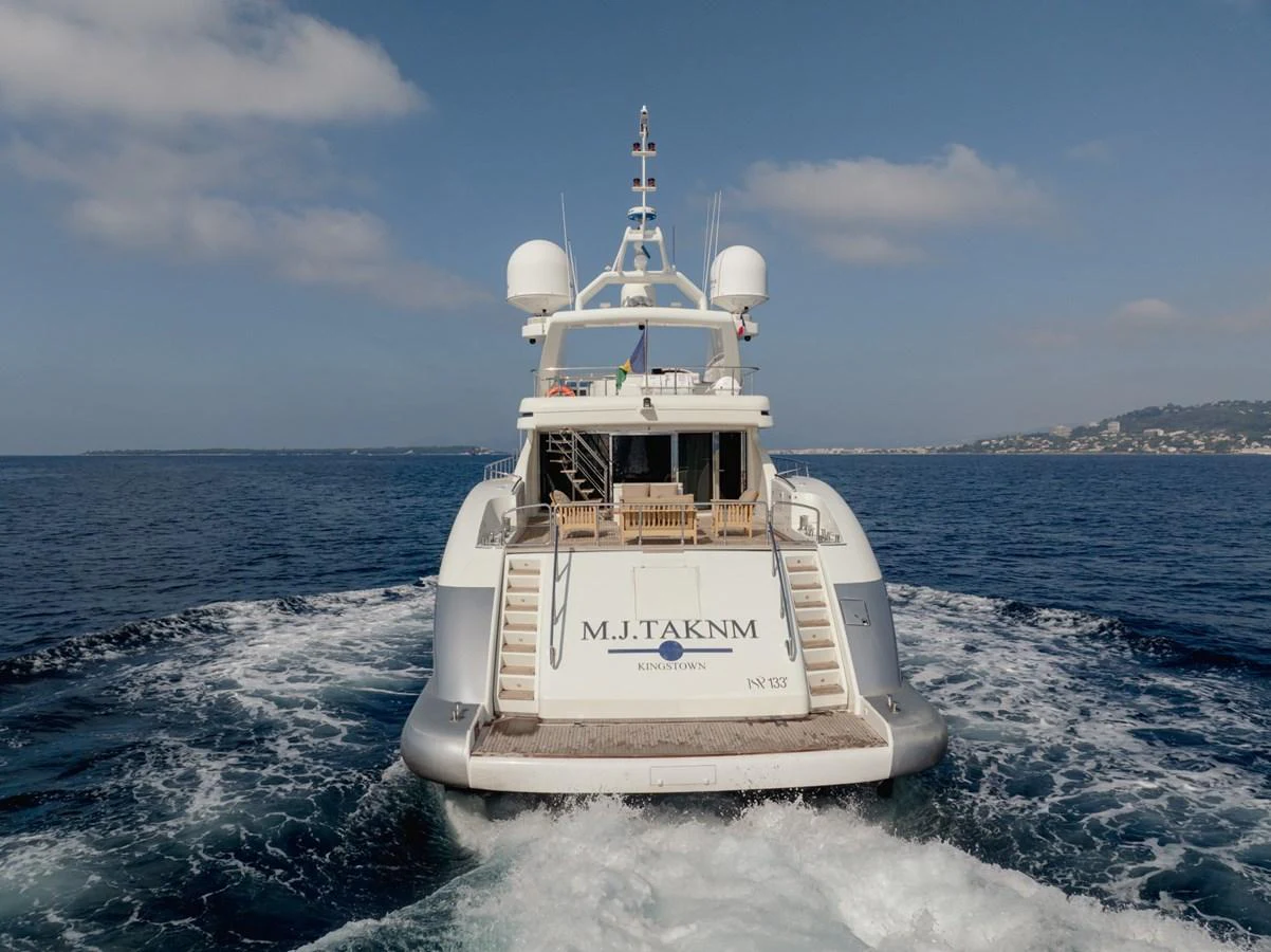 The yacht is cruising on the open sea, showcasing its spacious aft deck and sleek design. aboard M.J. TAKNM Yacht for Sale