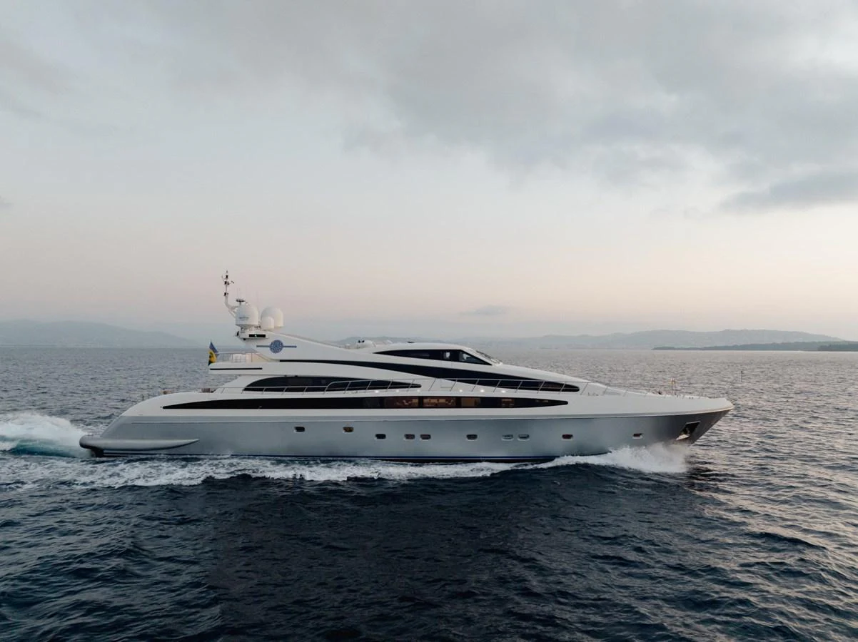 A sleek and modern yacht cruises gracefully on the open water at sunset. aboard M.J. TAKNM Yacht for Sale