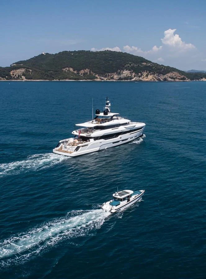 A luxurious yacht cruises through clear blue waters with a scenic island backdrop. aboard ATTITUDE Yacht for Sale