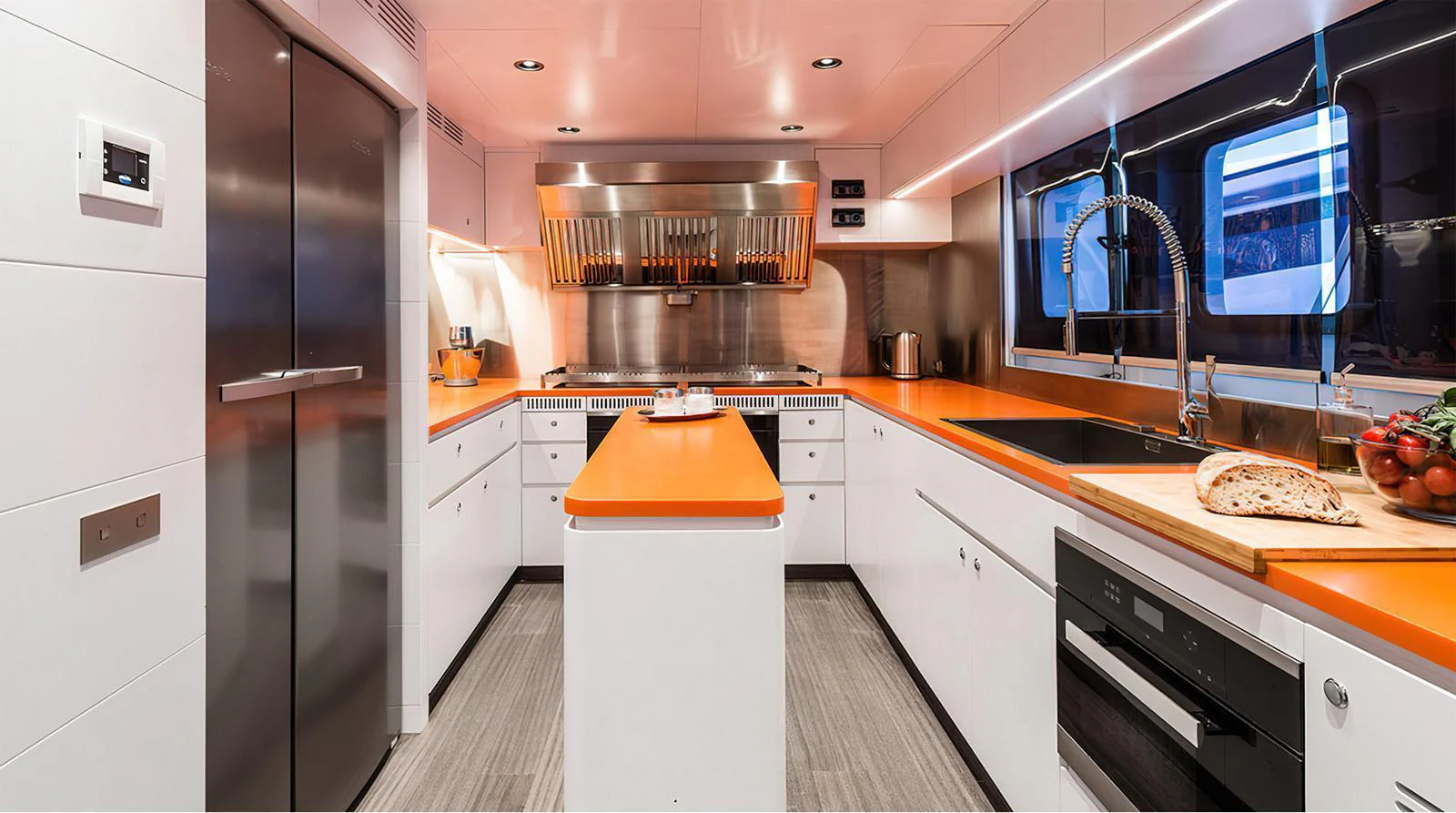 The galley features modern appliances and vibrant orange countertops, creating a stylish and functional space for culinary endeavors. aboard EXPLORER 130 Yacht for Sale