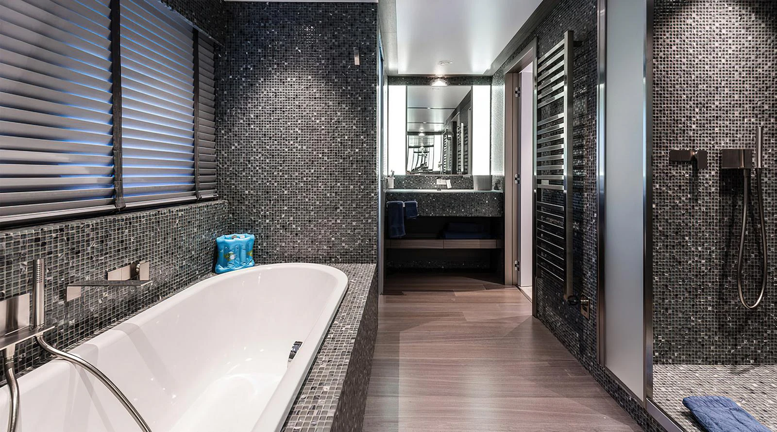 The yacht's bathroom features a luxurious bathtub and modern fixtures, complemented by sleek, dark mosaic tiles. aboard EXPLORER 130 Yacht for Sale