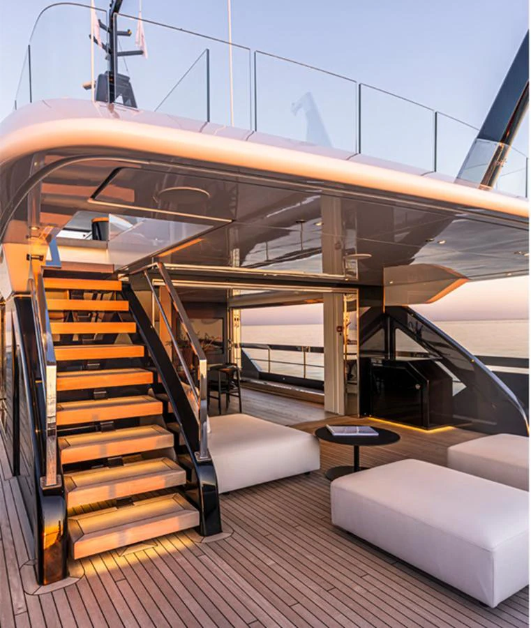 The aft deck features a stylish staircase leading to the upper deck, with comfortable seating and a serene ocean view. aboard DOGE 500 Yacht for Sale