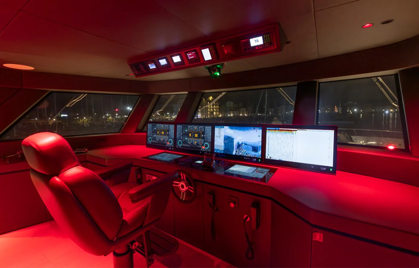 The helm station is illuminated with red lighting, featuring advanced navigation screens and a comfortable captain's chair. aboard DOGE 500 Yacht for Sale