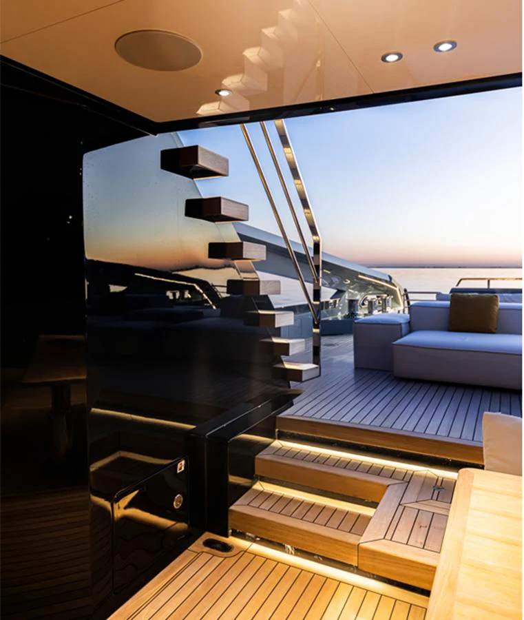 A sleek staircase leads to a luxurious deck with comfortable seating and a stunning sunset view. aboard DOGE 500 Yacht for Sale