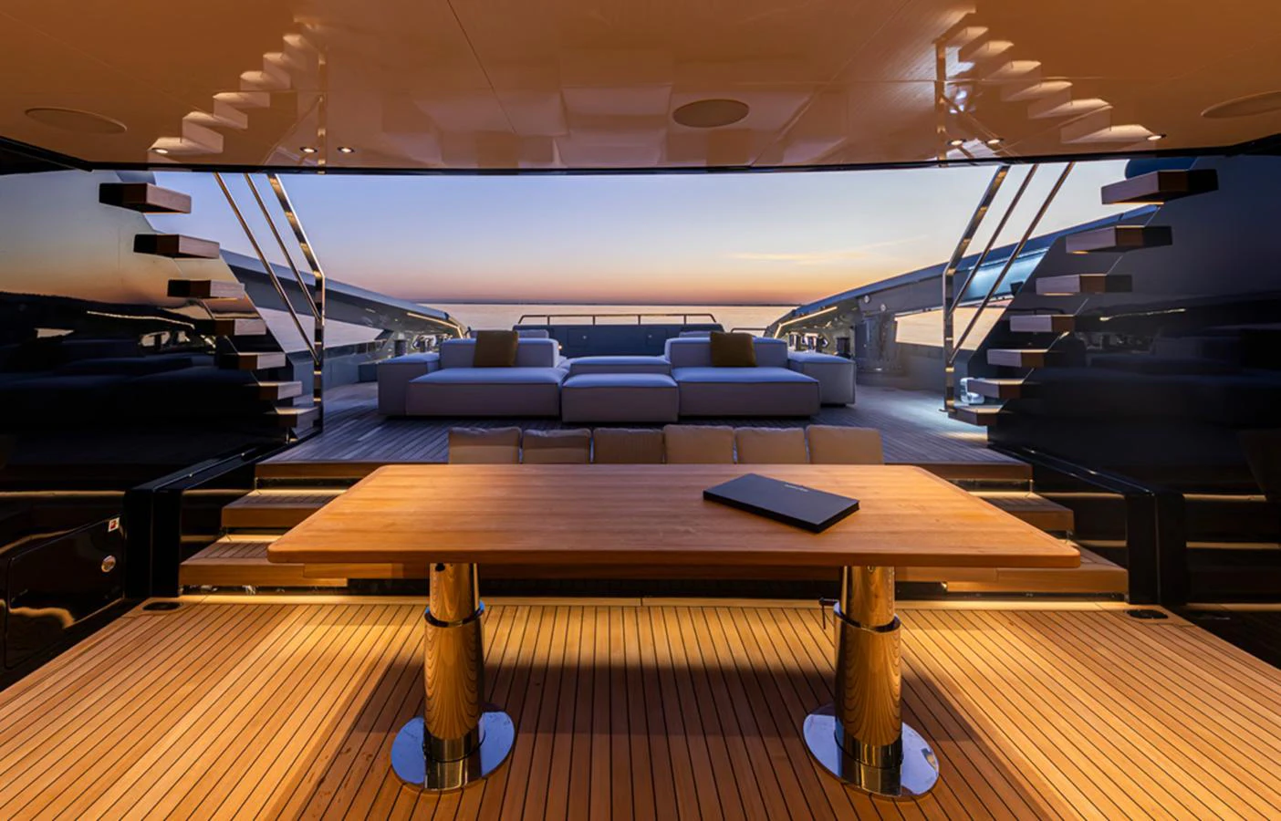 The aft deck features a spacious lounging area with modern furnishings and a stunning view of the sunset. aboard DOGE 500 Yacht for Sale