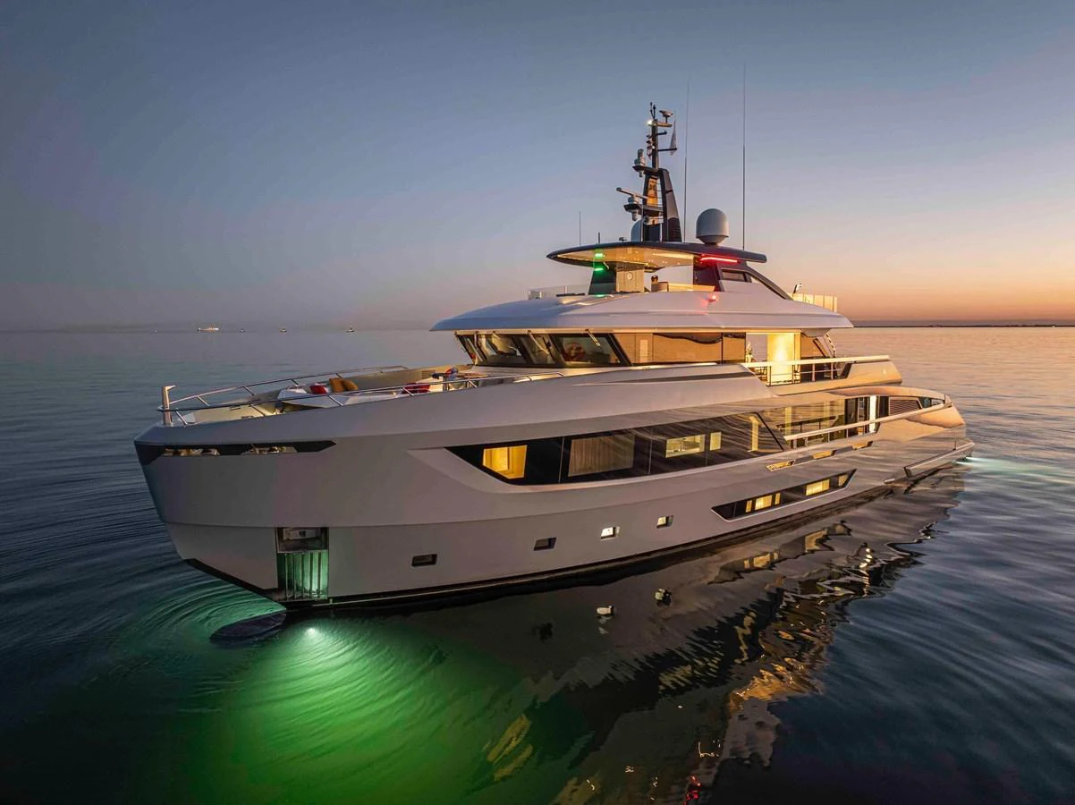 A sleek and modern yacht is beautifully illuminated at dusk, reflecting on calm waters. aboard DOGE 500 Yacht for Sale