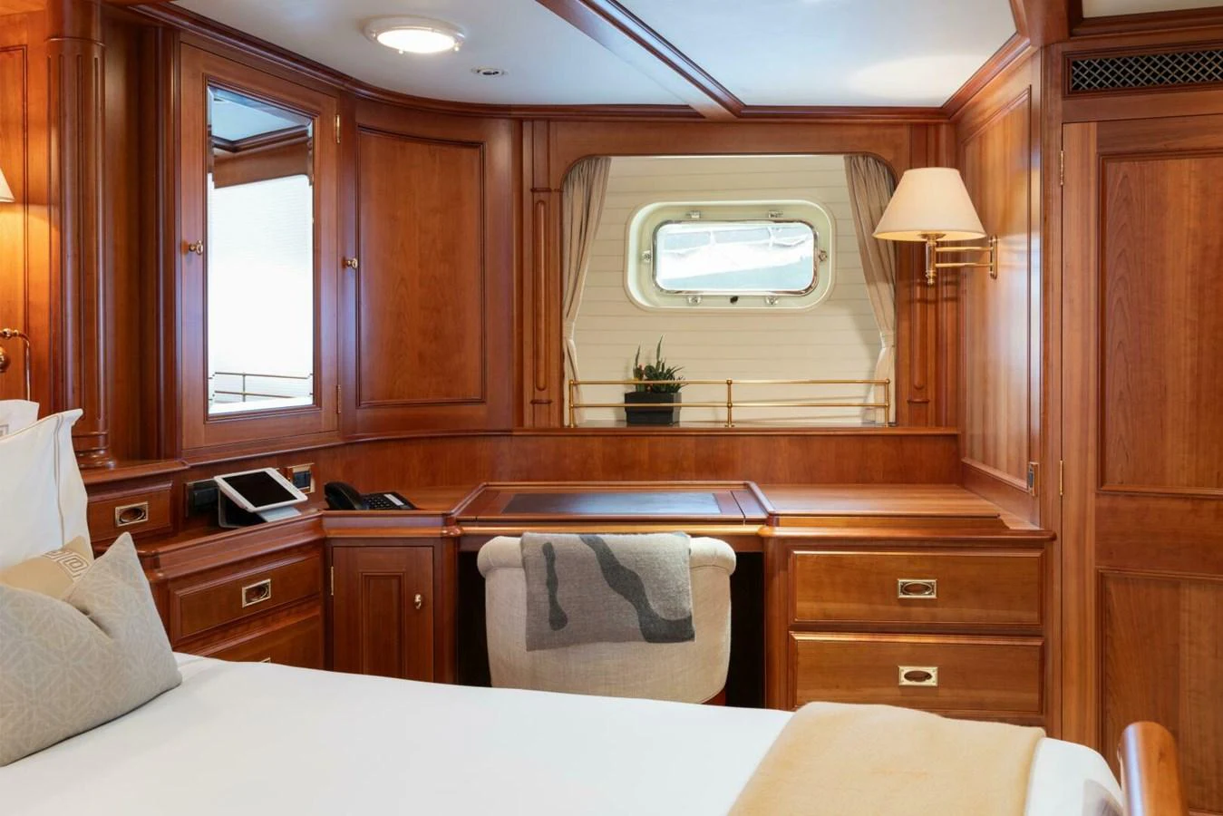 A cozy stateroom with rich wood paneling and a desk area, featuring a window with a view of the sea. aboard CATALINA Yacht for Sale