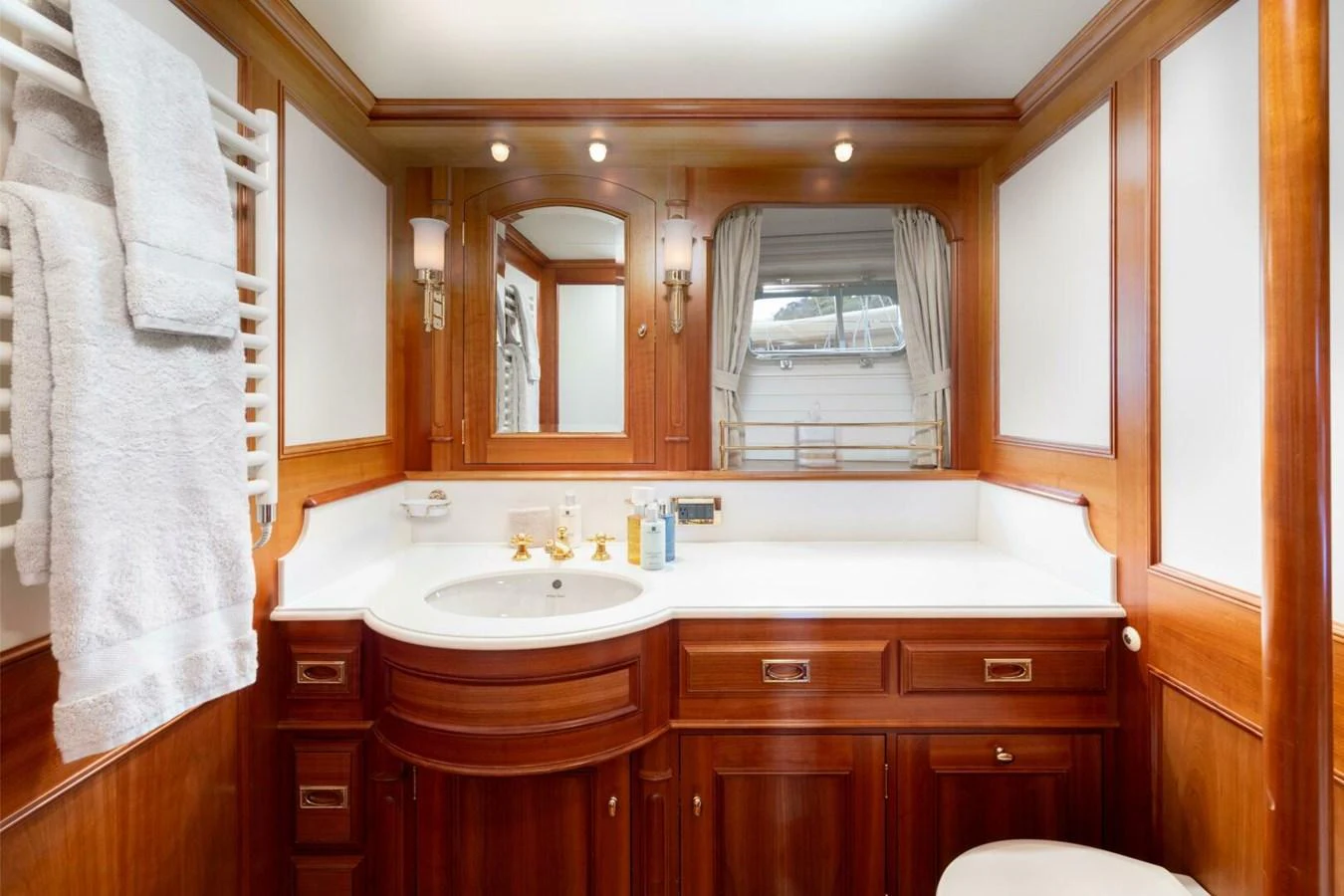 The yacht's bathroom features elegant wooden cabinetry and a pristine white countertop. aboard CATALINA Yacht for Sale