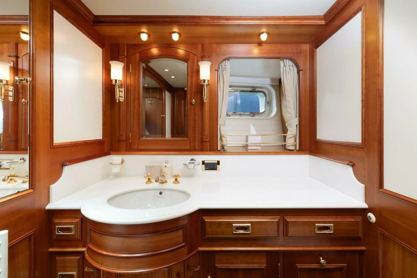 The yacht's bathroom features elegant wooden cabinetry and a pristine white countertop. aboard CATALINA Yacht for Sale