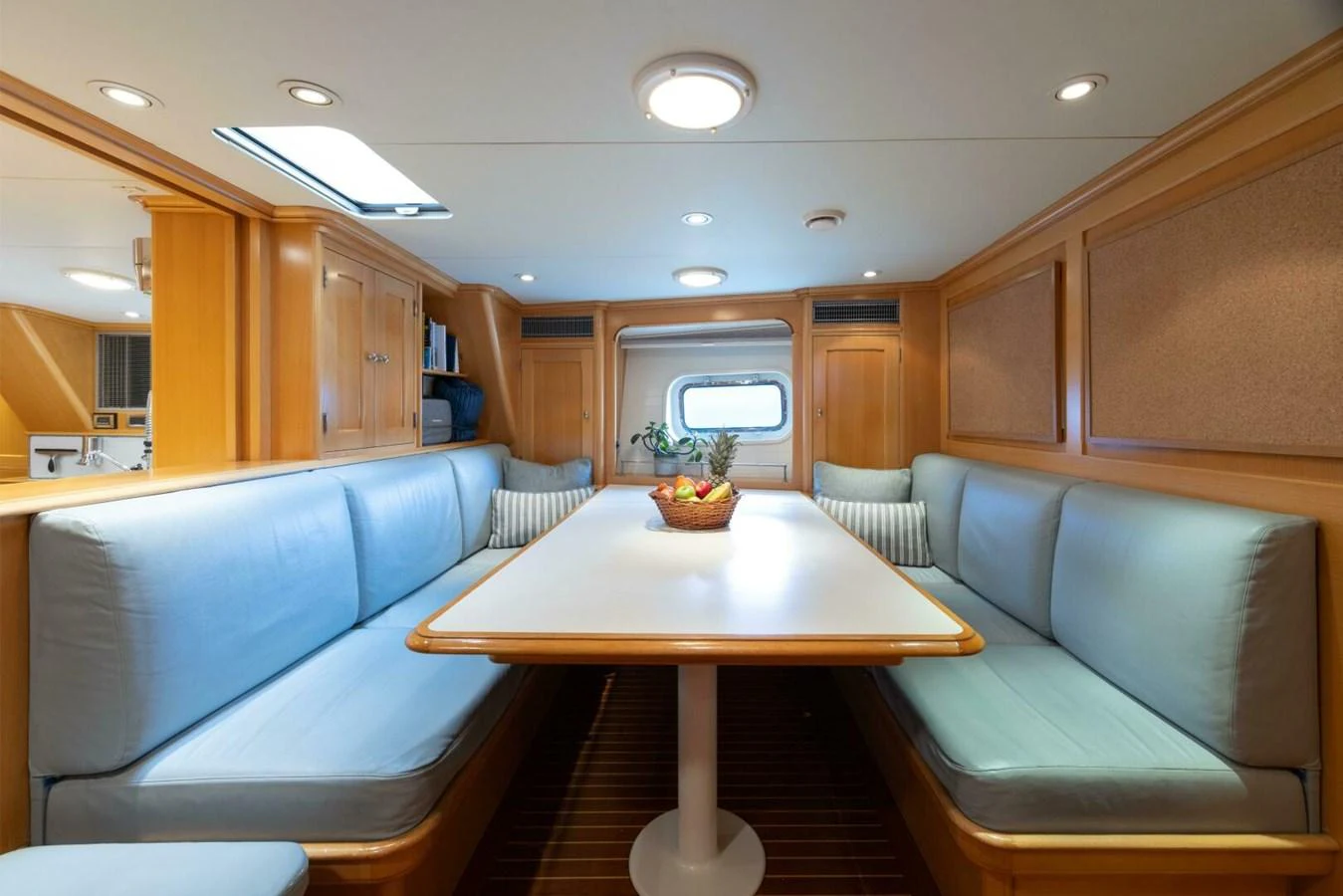 The yacht's dining area features a cozy seating arrangement with a central table, surrounded by light wood finishes and soft blue cushions. aboard CATALINA Yacht for Sale