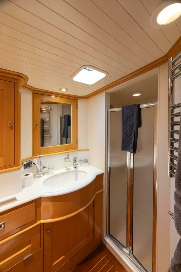 The yacht's bathroom features elegant wood cabinetry and a modern shower area. aboard CATALINA Yacht for Sale