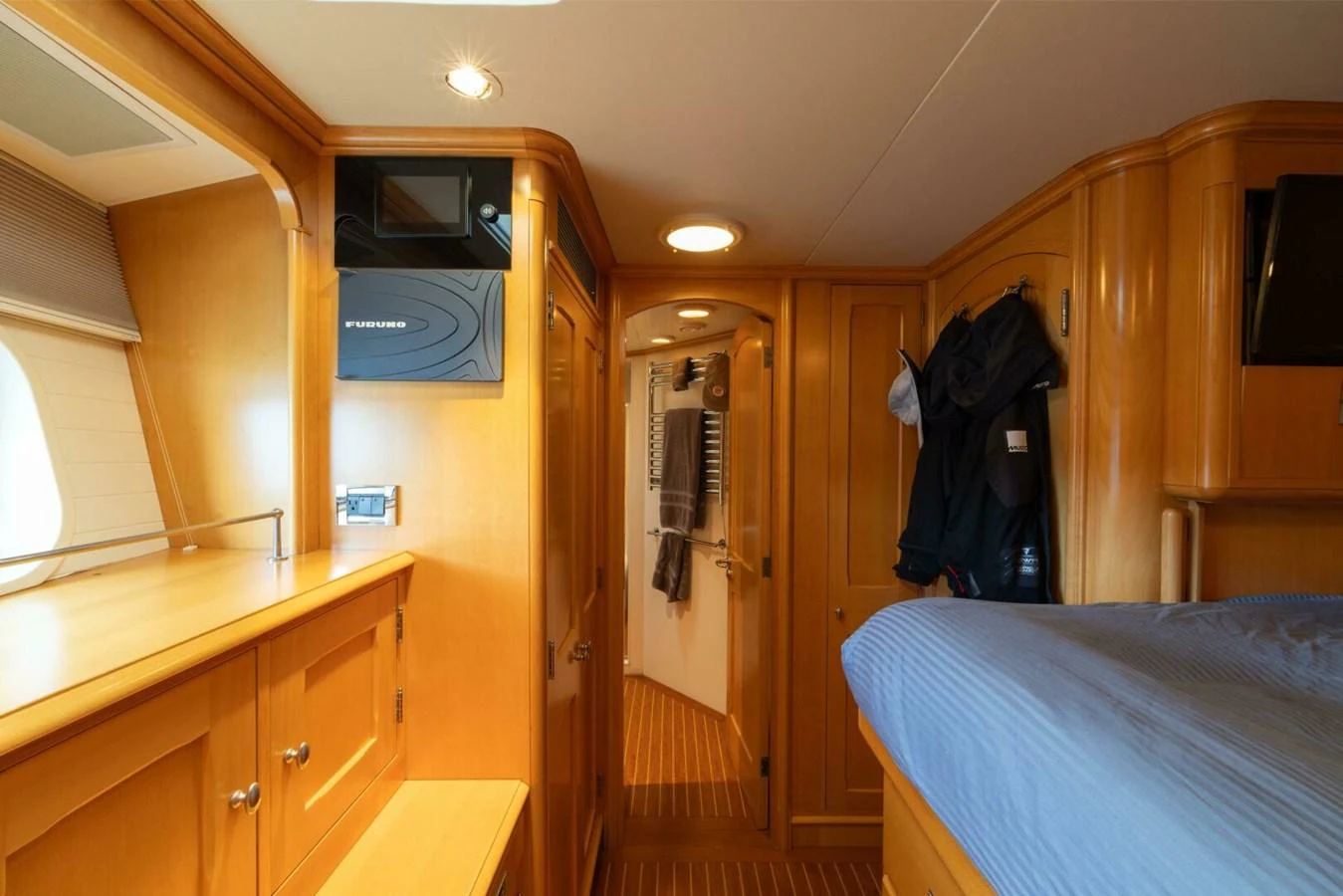 The cozy cabin features warm wood finishes and a comfortable bed with a blue cover. aboard CATALINA Yacht for Sale