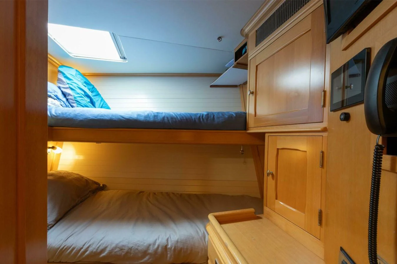 The cozy bunk cabin features wooden cabinetry and a skylight for natural light. aboard CATALINA Yacht for Sale