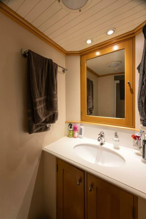 A well-appointed yacht bathroom with a sink, mirror, and wooden cabinetry. aboard CATALINA Yacht for Sale