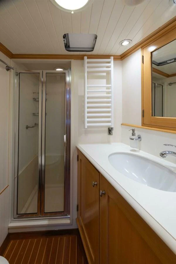 A well-appointed yacht bathroom with a shower, sink, and wooden cabinetry. aboard CATALINA Yacht for Sale